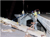 Workers install steel beams for the new bridge over railroad tracks