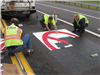 Fairfield's resident sign craftsmen, Wes and Jason, install the pre-formed thermoplastic pavement markings for No Thru Trucks in the lanes that lead to Ross Road