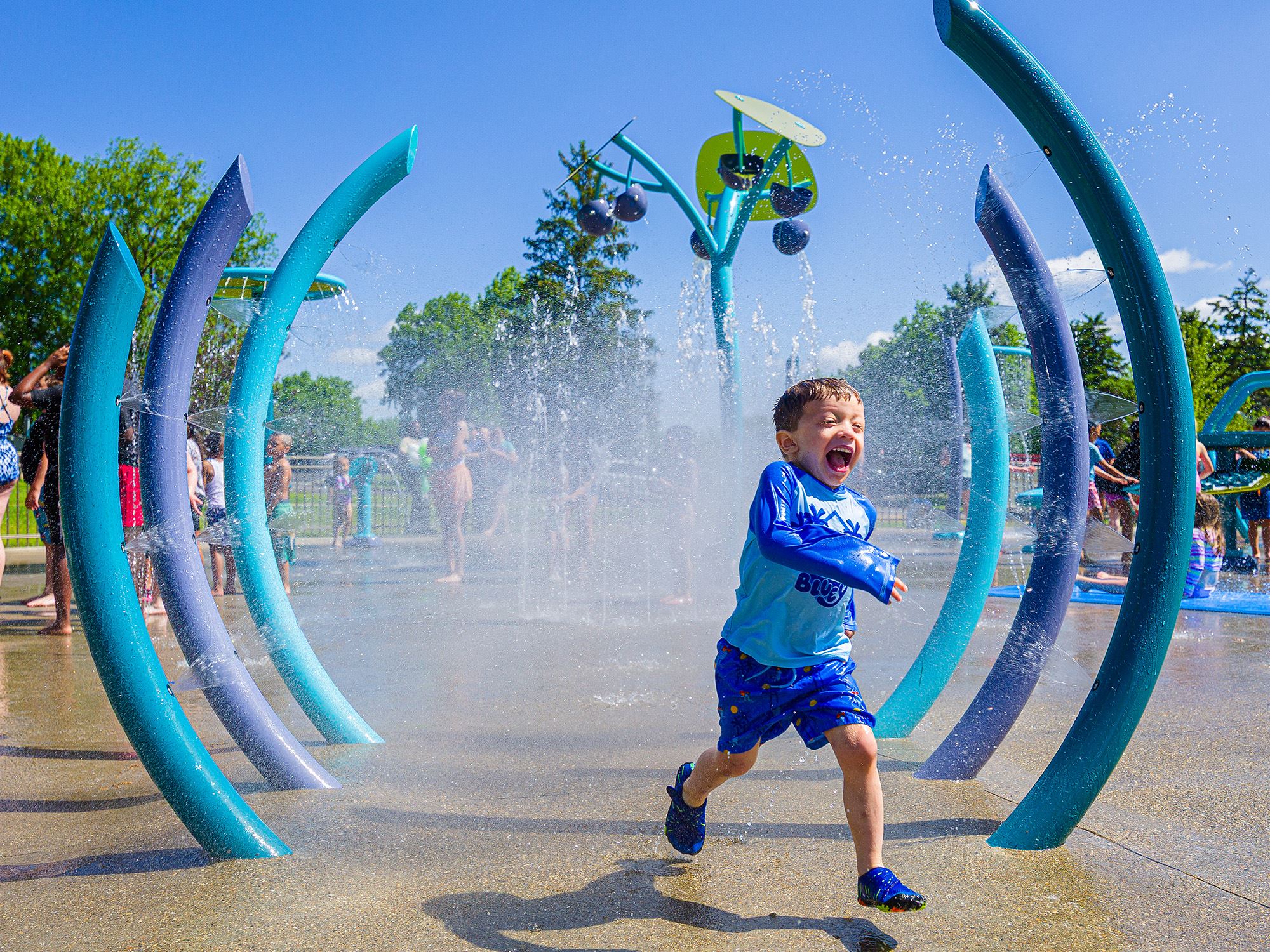 Child running through splash pad water rings