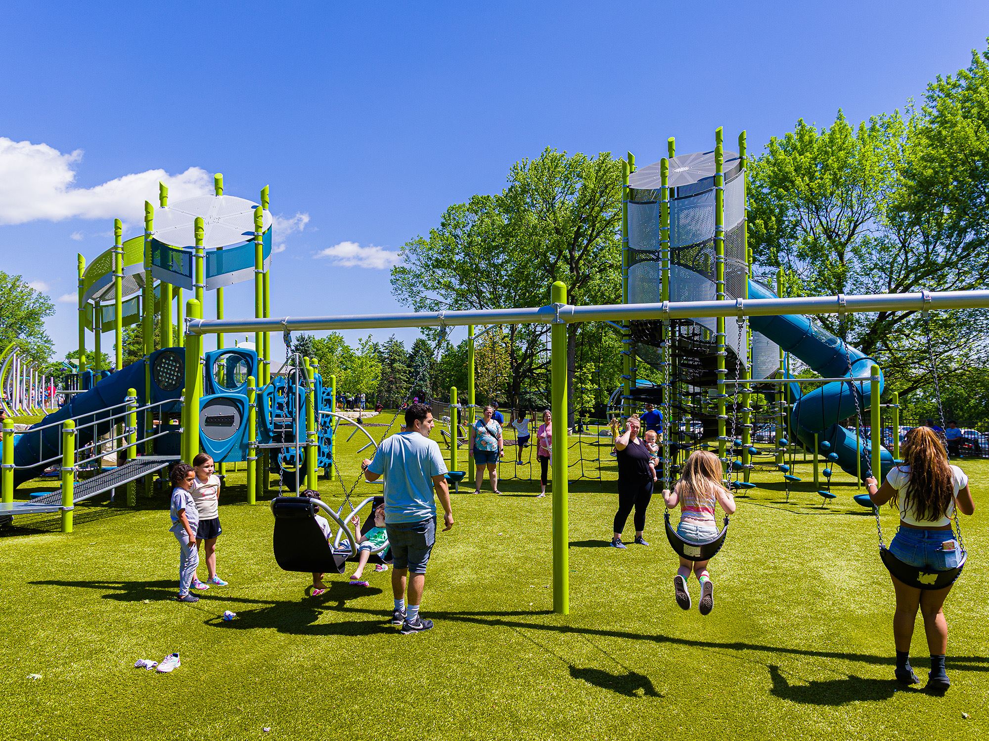 Families enjoying swings and slides at new playground