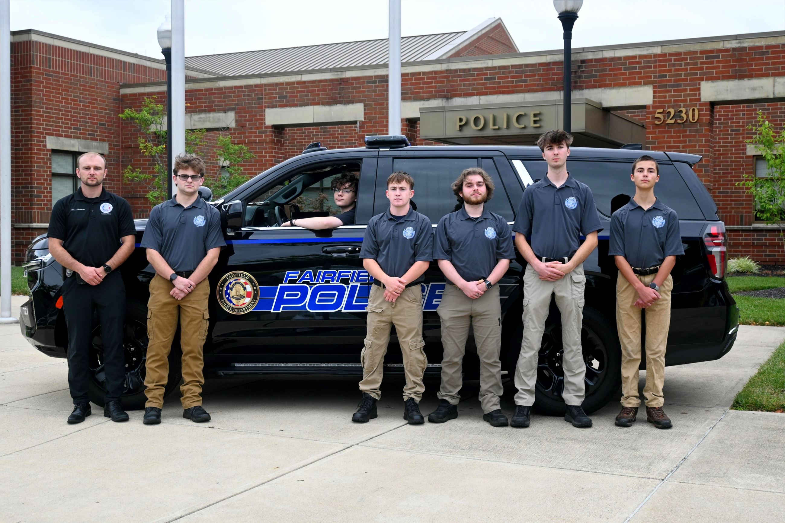 Public Safety Cadets standing in front of a Fairfield PD cruiser parked next to the Police entrance